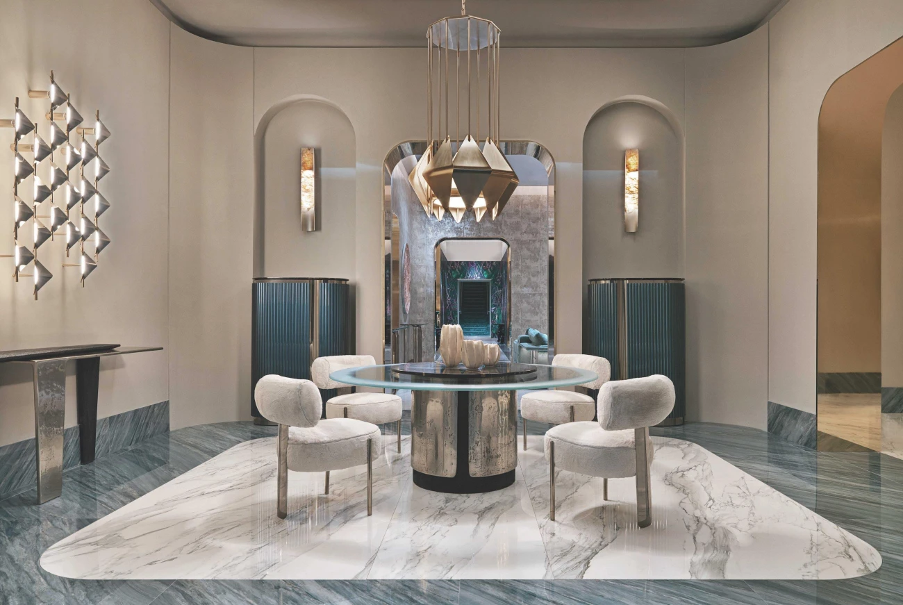 Luxusní jídelní kout s dominantním kulatým stolem, měkkým čalouněním a výrazným závěsným svítidlem je dokonalou ukázkou moderního designu, který propojuje umění a funkčnost v harmonickém celku.